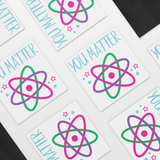 You_Matter_Funny_Atom_Science_Car_Magne_SquareCarMagnet_Scattered_Mockup.png
